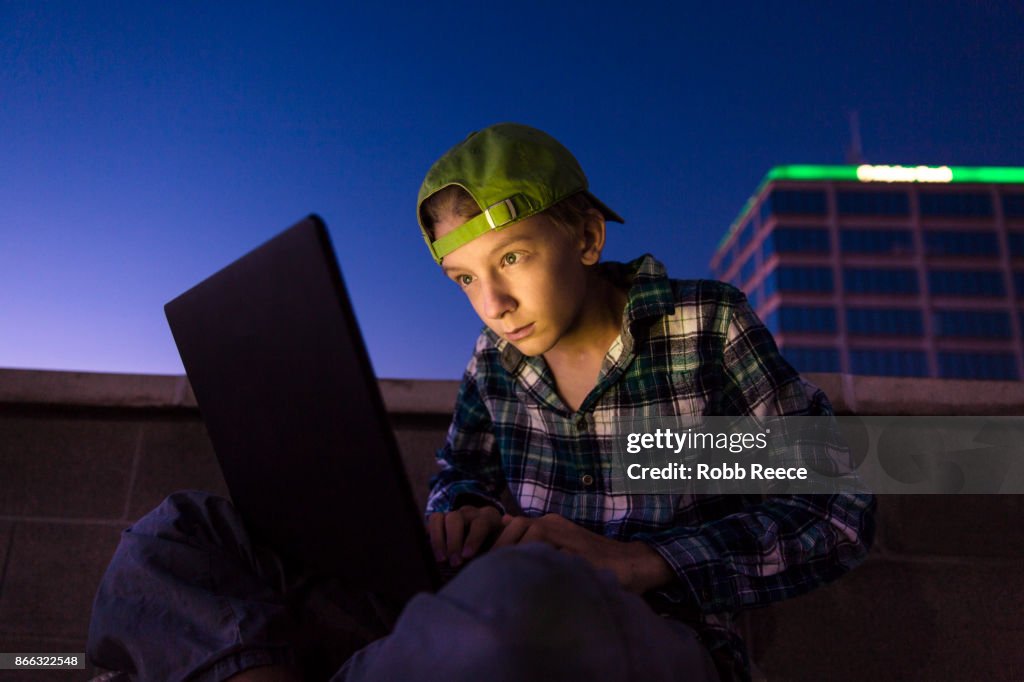 A teenage boy hacking with a laptop computer to commit cyber crime