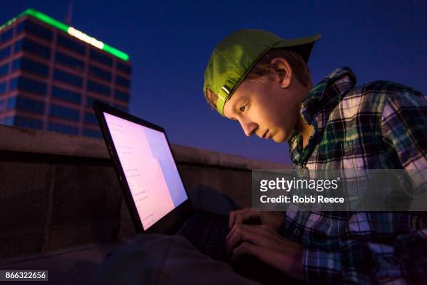 a teenage boy hacking with a laptop computer to commit cyber crime - robb reece imagens e fotografias de stock