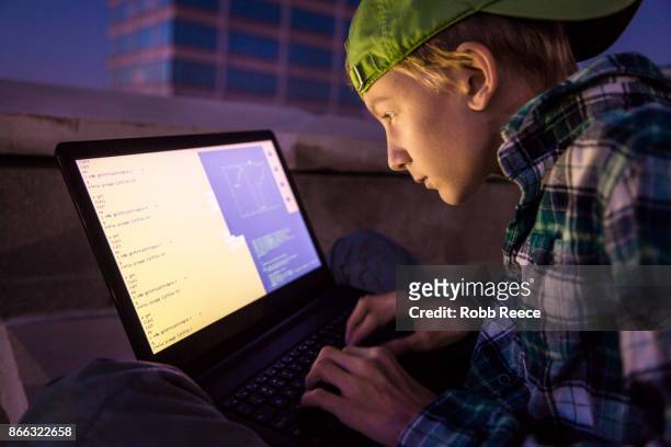 a teenage boy hacking with a laptop computer to commit cyber crime - robb reece imagens e fotografias de stock