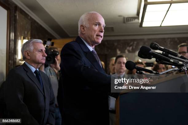 Sen. Jack Reed look on as Sen. John McCain speaks during a brief press conference before an Armed Services conference committee meeting on the...