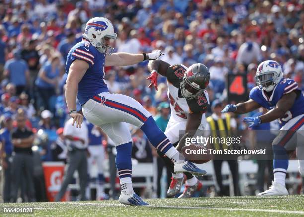 Colton Schmidt of the Buffalo Bills punts the ball during NFL game action as Peyton Barber of the Tampa Bay Buccaneers tries to get to him at New Era...