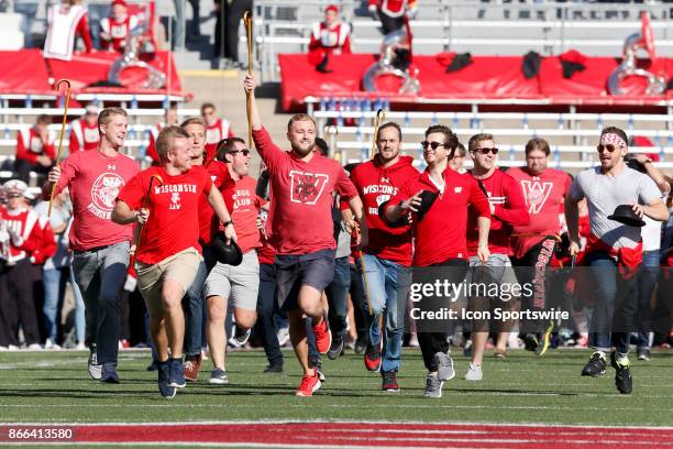 Third year Wisconsin law students run the length of the field and attempt to toss a cane over the goal post during a Big Ten football game between...
