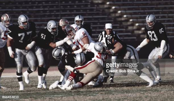 Los Angeles Raiders Lyle Alzado , Howie Long and Ted Hendricks surround 49'ers running back during San Francisco vs Los Angeles Raiders game, August...
