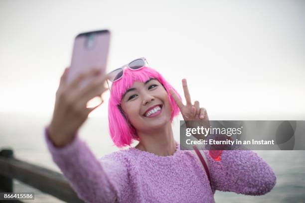 young woman with pink hair taking a selfie - warm roze stockfoto's en -beelden