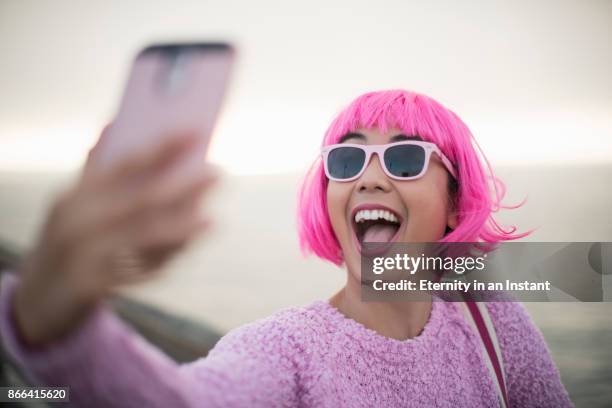 young woman with pink hair taking a selfie - holding sunglasses stockfoto's en -beelden