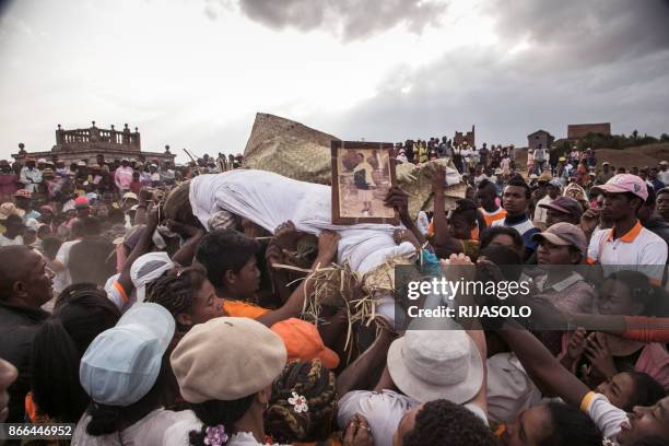 People carry a body wrapped in a sheet after taking it out from a crypt, as they take part in a funerary tradition called the Famadihana in the...