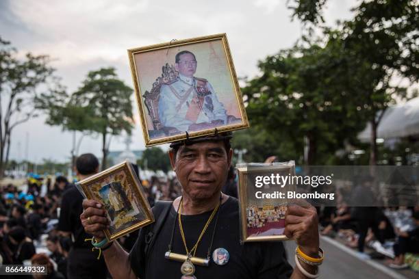 Man holds portraits of the late King Bhumibol Adulyadej near the Royal Crematorium ahead of the cremation of the King in Bangkok, Thailand, on...