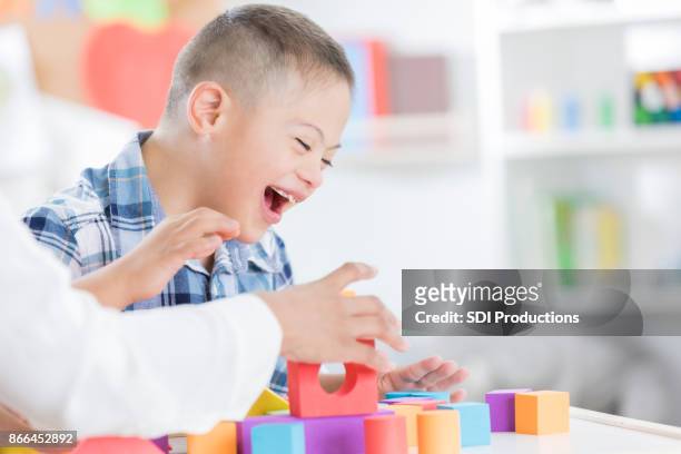 unrecognizable teacher helps young boy with blocks - special needs children stock pictures, royalty-free photos & images