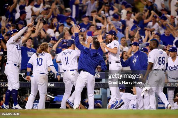 Logan Forsythe of the Los Angeles Dodgers celebrates with teammates after scoring a run on a RBI single hit by Enrique Hernandez to tie the game 5-5...