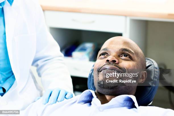 happy dental patient smiles up at unseen dentist - dentist's chair stock pictures, royalty-free photos & images