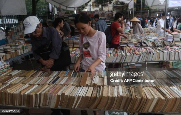 Girl browses used books on display for sale at a local used books fair in Hanoi on October 26, 2017. / AFP PHOTO / HOANG DINH NAM