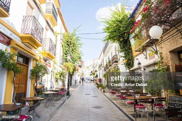 people visiting the beautiful narrow streets in the south of spain with white houses and vegetation with flowers during trip in the sunny andalucia. - costa del sol - fotografias e filmes do acervo