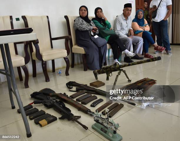 Residents waiting for their safe conduct papers, watch as soldiers display home-made barrett sniper, and other weapons recovered from Muslim...