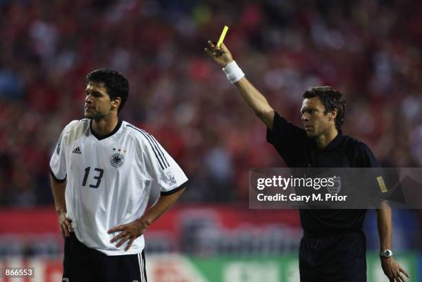 Referee Urs Meier of Switzerland shows the yellow card to Michael Ballack of Germany which due to a previous booking means he will miss the final...