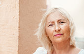 Portrait of beautiful senior woman with white hair standing by wall.