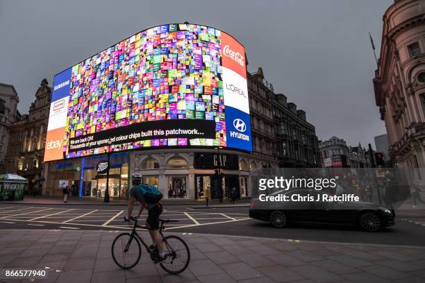 Members of the public watch as an animation is seen after the countdown as the Piccadilly Circus lights are switched back on after a nine month...