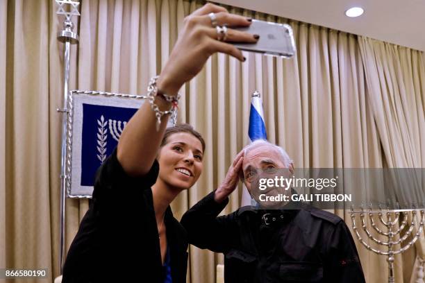 French-Armenian singer Charles Aznavour adjusts his hair as he does a selfie with a fan on October 26, 2017 at the presidential compound in...