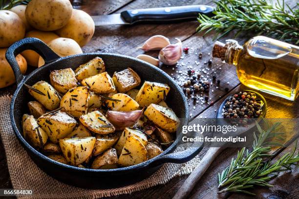 roasted potatoes on wooden kitchen table - basic food stock pictures, royalty-free photos & images