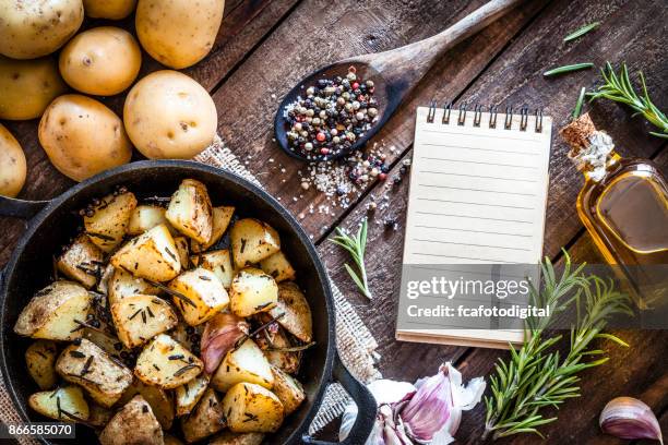 roasted potatoes with cookbook on wooden kitchen table - prepared potato stock pictures, royalty-free photos & images