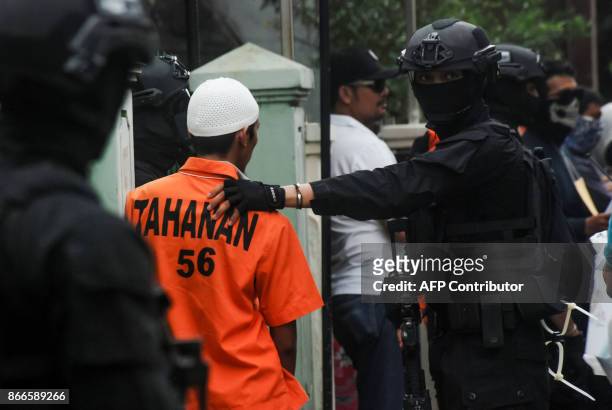 Densus 88 anti-terror police escort an alleged terror suspects during a reconstruction in Mekarsari, in Bandung, West Java province, on October 26,...