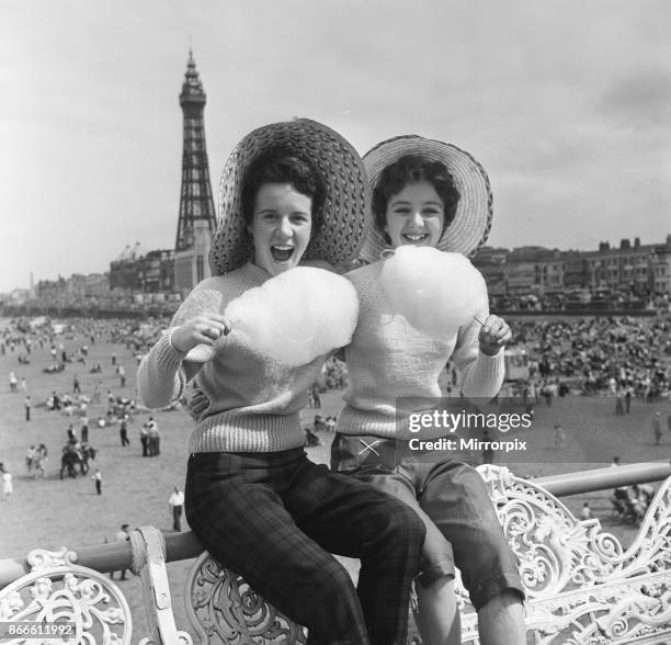 Jean Clark and Mary Cuppler enjoy eating candy floss on the pier at Blackpool, Lancashire, 18th July 1957.