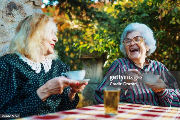 senior women drinking coffee and laughing - sharing coffee stock pictures, royalty-free photos & images