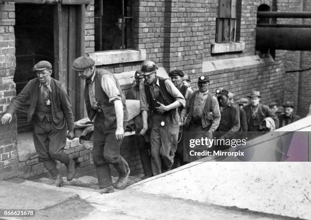 Stretcher party heads the line of rescue workers as they come to bank after an exhausting spell below. Rescue teams and volunteers worked valiantly...