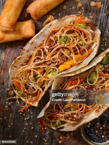 asian/mexican fusion - teriyaki beef and noodle tacos - fusion food stock pictures, royalty-free photos & images