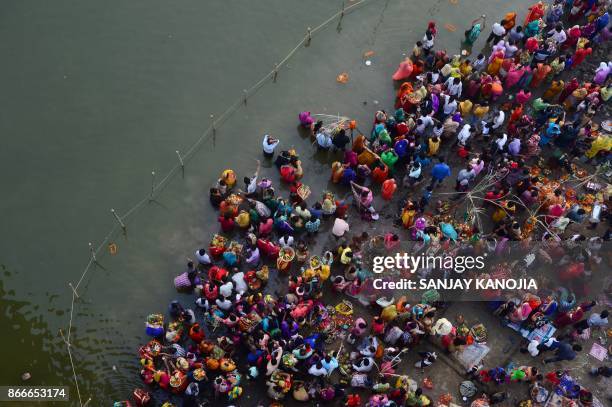 Indian Hindu devotees perform religious rituals as they offer prayers to the sun god on the banks of the Yamuna river during the Chhath Festival in...
