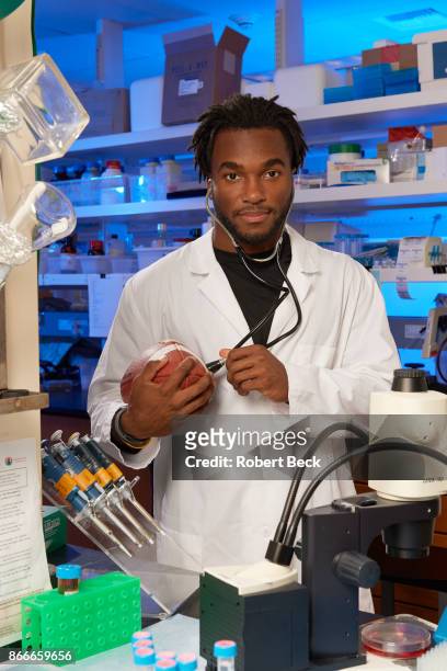 Portrait of Stanford running back Bryce Love posing in lab coat with stethoscope and football during photo shoot at Stanford Universtiy Stem Cell...