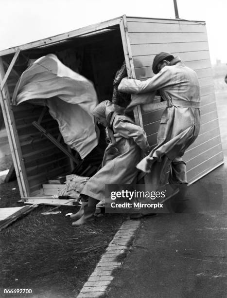 Gale damage. A couple cling desperately to their overturned beach hut at Littlehampton to stop it being blown away. Littlehampton, West Sussex, 29th...