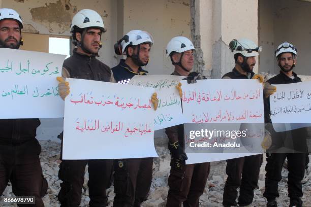 Group of civil defense crew members hold banners as they stage a demonstration, calling for help to end the Assad Regime's Ghouta siege causing child...