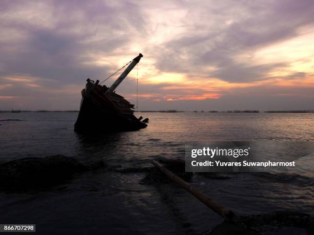 wrecked boat on a silent sea in sunset and golden twilight sky. - sinking ship stock-fotos und bilder