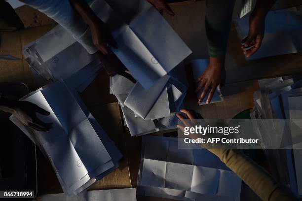 Independent Electoral and Boundaries Commission officials count presidential ballots at a polling station in Nairobi on October 26, 2017 following a...