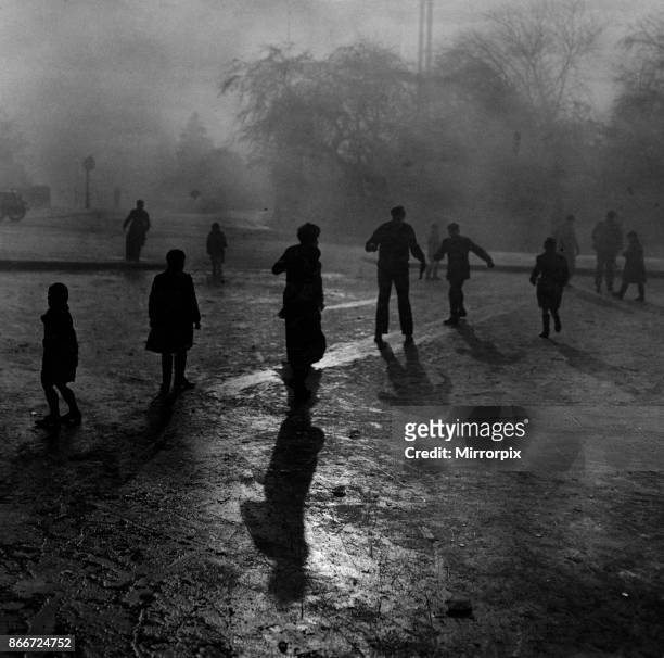 Fog and ice on Hampstead Heath. Boys sliding on the ice in the fog at Hampstead Heath ponds. Although the weather was wintry and the fog was thick,...