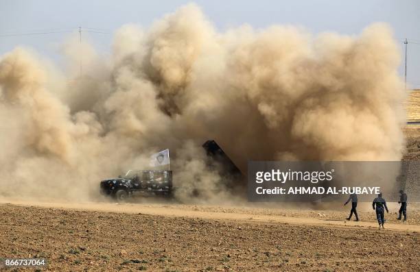 Picture taken on October 26, 2017 shows dust clouds swirling around an Iraqi security forces' rocket launcher after firing against Kurdish Peshmerga...
