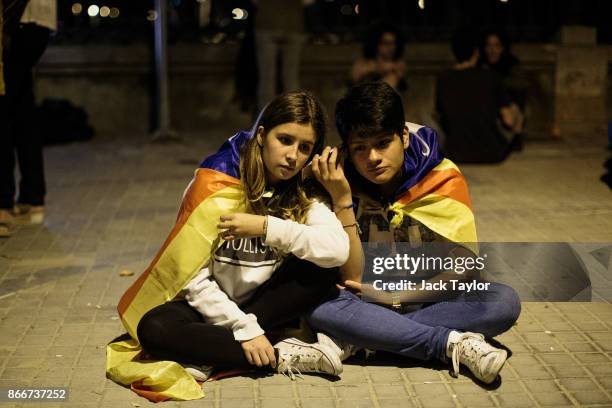 People listen to Catalan Parliament proceedings through a mobile phone as Catalan independence supporters gather outside the Parliament of Catalonia...