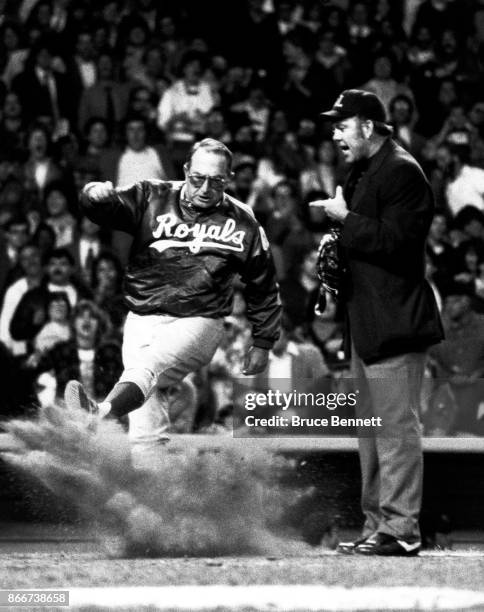 Manager Jim Frey of the Kansas City Royals kicks dirt onto home plate after disagreeing with a call by umpire Dale Ford during an MLB game against...
