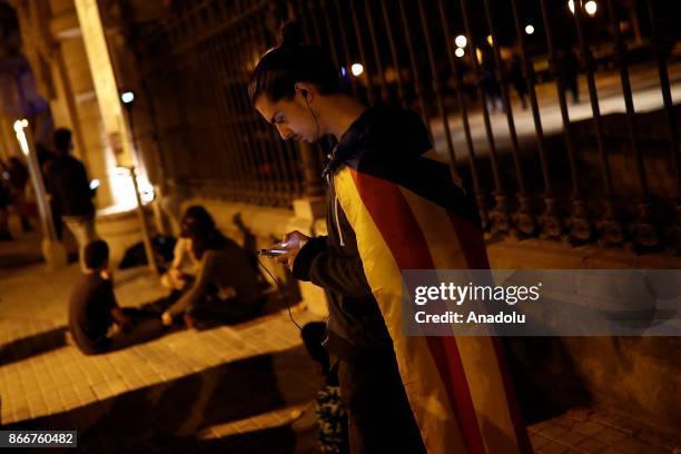 Supporter of Catalonia's independence follows the Catalonian Parliament's plenary session via a smart phone in front of the parliament in Barcelona,...