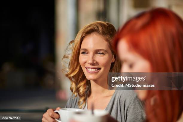 smiling woman having a coffee with a friend - selective focus imagens e fotografias de stock