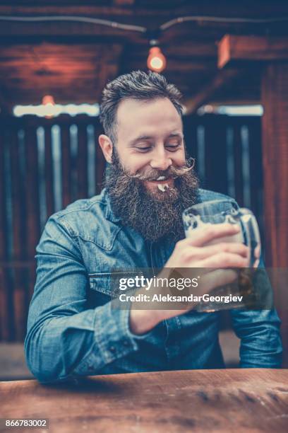knappe hipster persoon die het drinken van bier in pub - man sipping beer smiling stockfoto's en -beelden