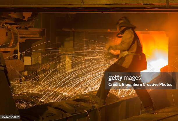 a worker supervises the flow of hot liquid metal as it flows from a furnace - norilsk stock pictures, royalty-free photos & images