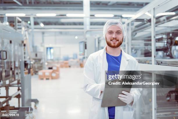 ung vacker leende vetenskapsman med urklipp poserar i fabriken - food service occupation bildbanksfoton och bilder