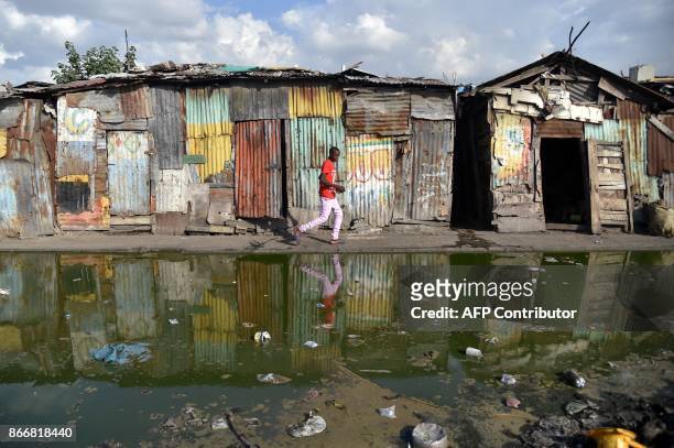 Boy walks on a street in the La Saline neighborhood of Port-au-Prince on October 26 close to the Market of La Saline. / AFP PHOTO / HECTOR RETAMAL