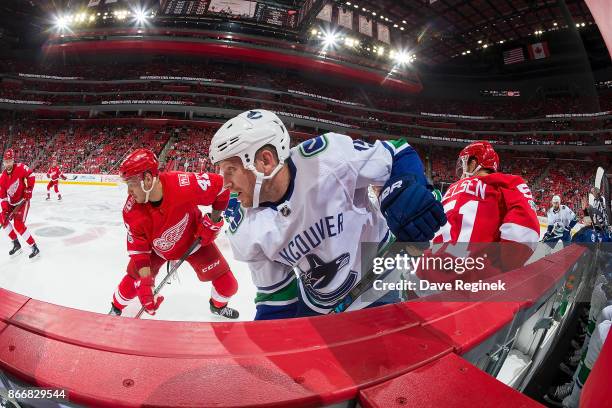 Derek Dorsett of the Vancouver Canucks battles along the boards with Martin Frk of the Detroit Red Wings during an NHL game at Little Caesars Arena...