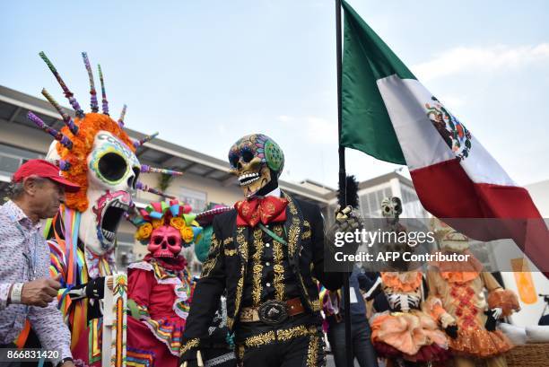 People disguised for celebrations in the framework of the Day of the Dead perform at the Hermanos Rodriguez racetrack in Mexico City, on October 26,...