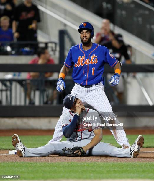 Amed Rosario of the New York Mets celebrates his triple at third base while Johan Camargo of the Atlanta Braves appears frustrated after Rosario beat...