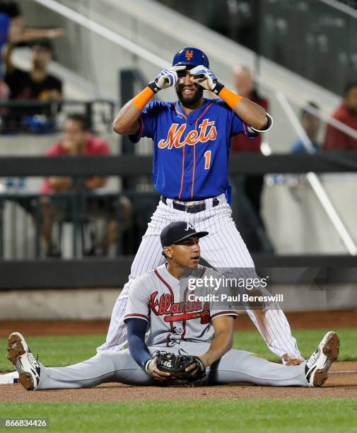 Amed Rosario of the New York Mets celebrates his triple at third base while Johan Camargo of the Atlanta Braves appears frustrated after Rosario beat...