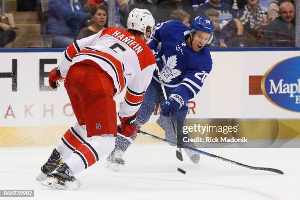 Toronto Maple Leafs center Dominic Moore lets a shot fly as Carolina Hurricanes defenseman Noah Hanifin closes in. Toronto Maple Leafs VS Carolina...