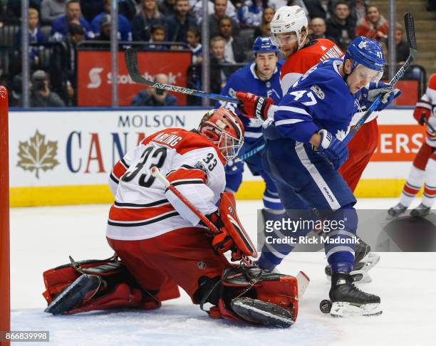 Toronto Maple Leafs center Leo Komarov uses his foot to try to redirect the puck in front of Carolina Hurricanes goalie Scott Darling . Toronto Maple...